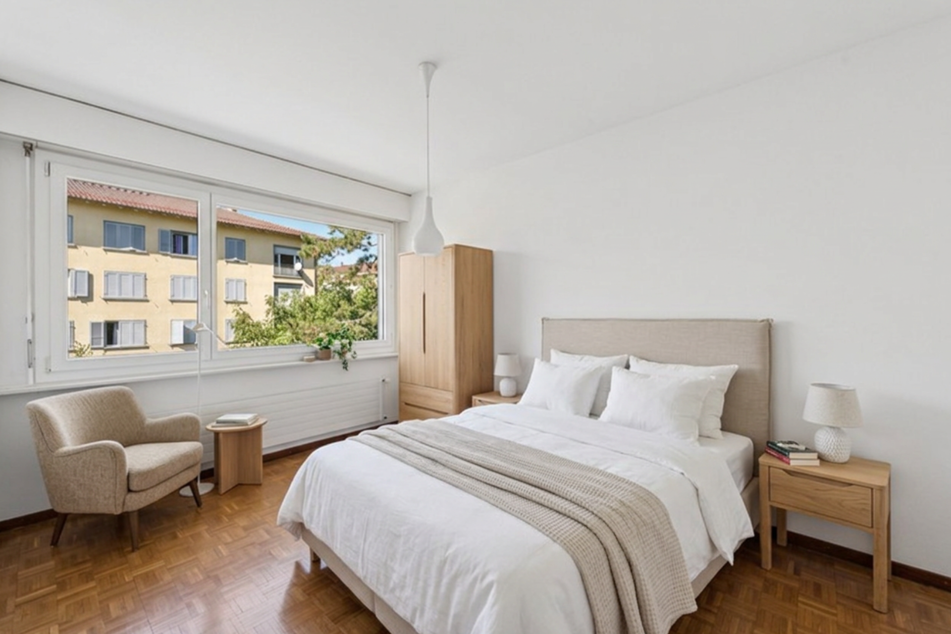 Master bedroom with parquet flooring and a large window