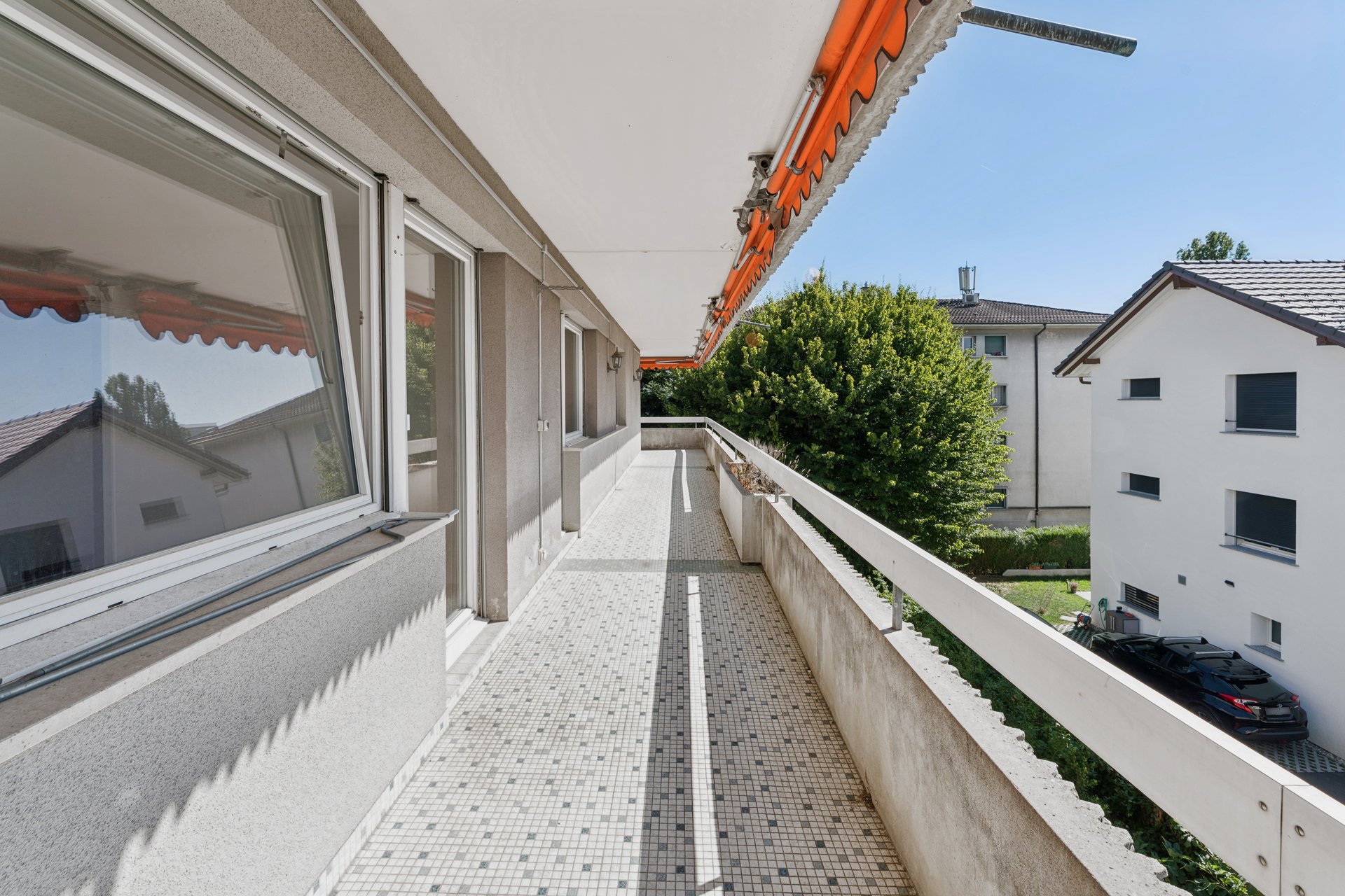 Long balcony running along the apartment, with a view over greenery